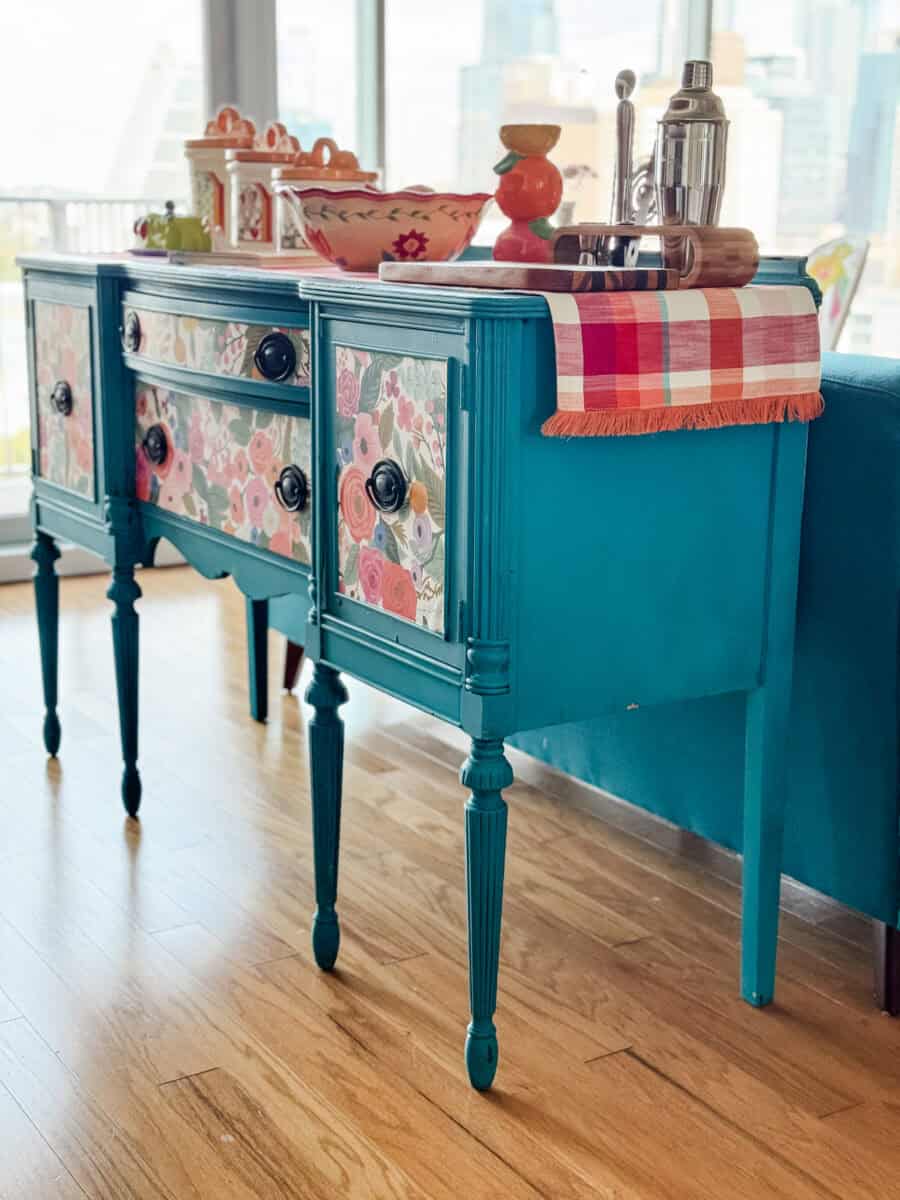 Styled as kitchen island – Teal sideboard buffet styled as a colorful kitchen island with dishes on top.