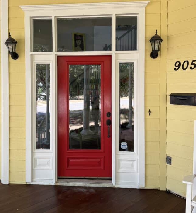 door before with pink paint and black sconces, black mailbox, and black house numbers