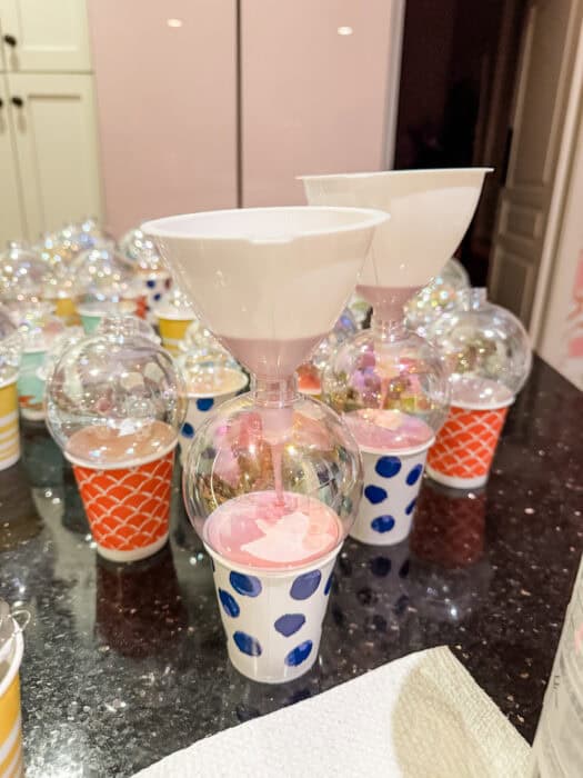 Painted ornaments drying upside down on small cups as excess paint drains out.
