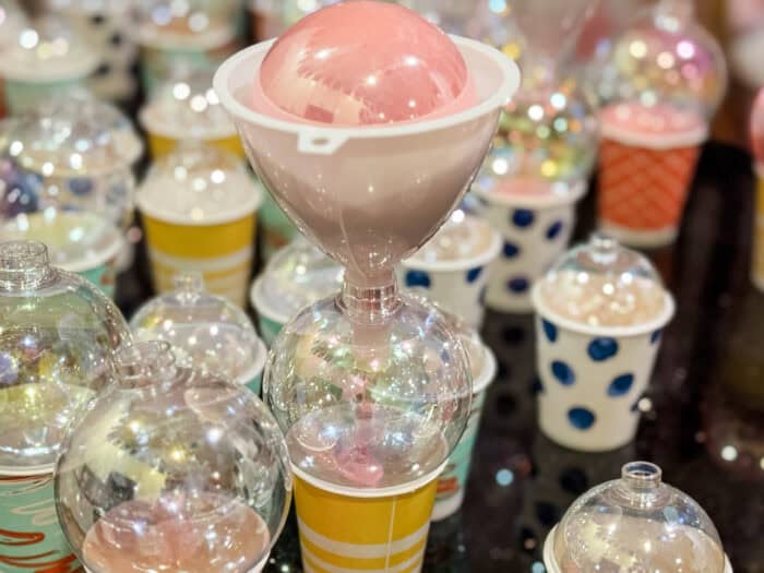 Painted ornaments drying upside down on small cups as excess paint drains out.