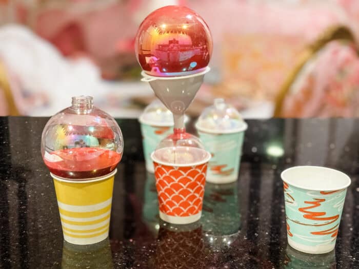 Painted ornaments drying upside down on small cups as excess paint drains out.