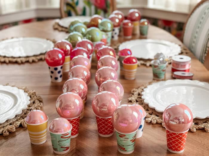 Painted ornaments drying upside down on small cups as excess paint drains out.