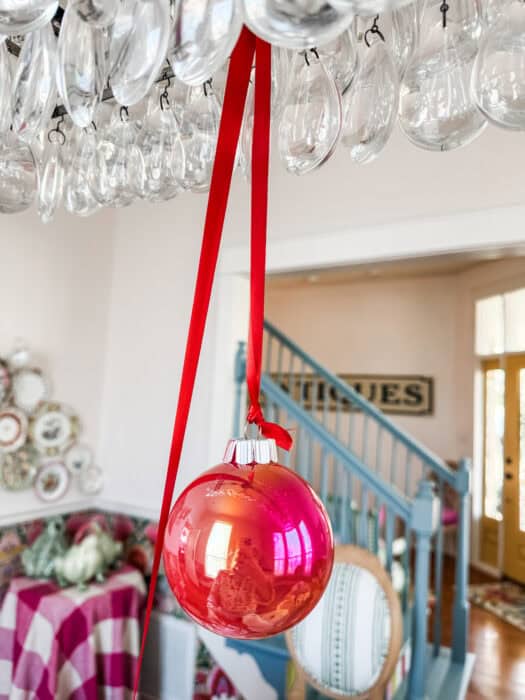 Red ornament hanging from chandelier with a red ribbon