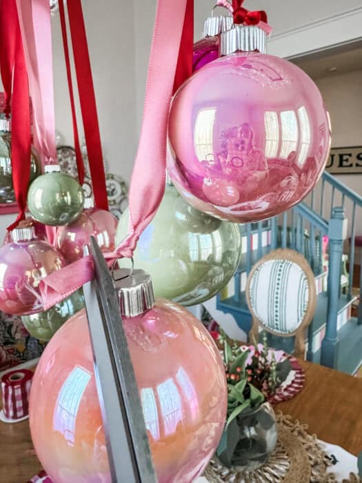 Strands of satin ribbon tied to the chandelier with ornaments hanging at staggered heights.