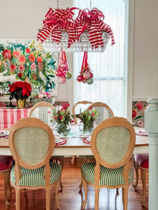 Full view of the dining room showing the Christmas chandelier decor, table setting, and colorful wallpaper.