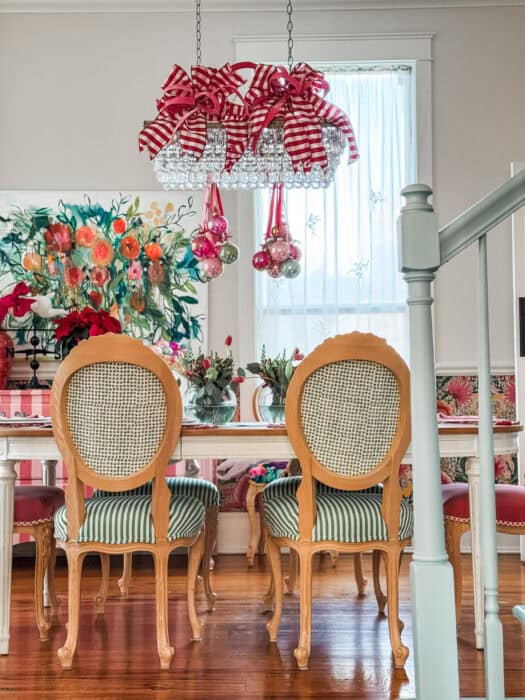 Full view of the dining room showing the Christmas chandelier decor, table setting, and colorful wallpaper.