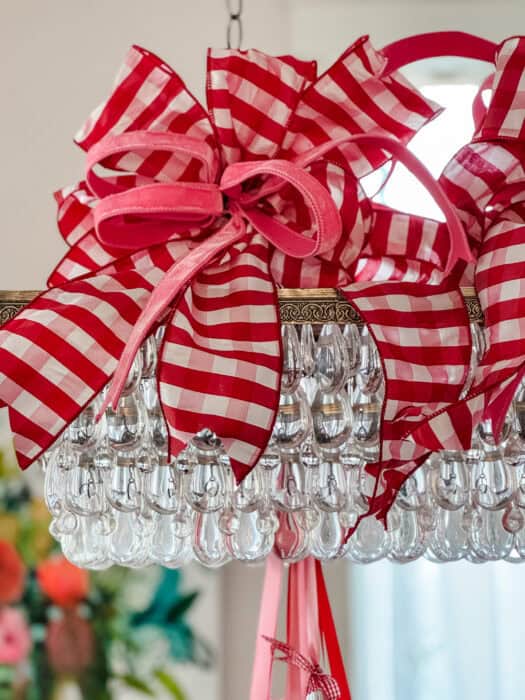 Oversized wired bows in pink and red gingham attached to the top of the chandelier for added holiday flair.