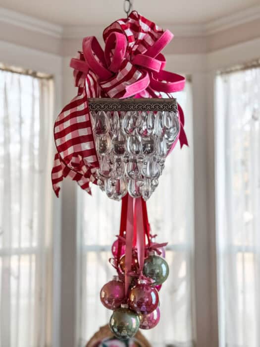 Oversized wired bows in pink and red gingham attached to the top of the chandelier for added holiday flair.