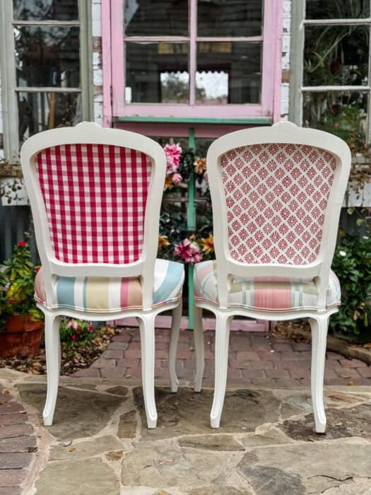 Backside of two chairs showing the check fabric in pink and the block print fabric in coral. 