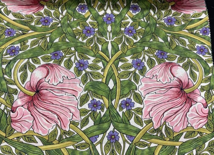 Morris & Co. fabric showing pink flowers on green leaves and vines. 