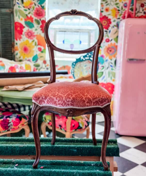 Before chair picture with brown frame and pink velvet fabric.