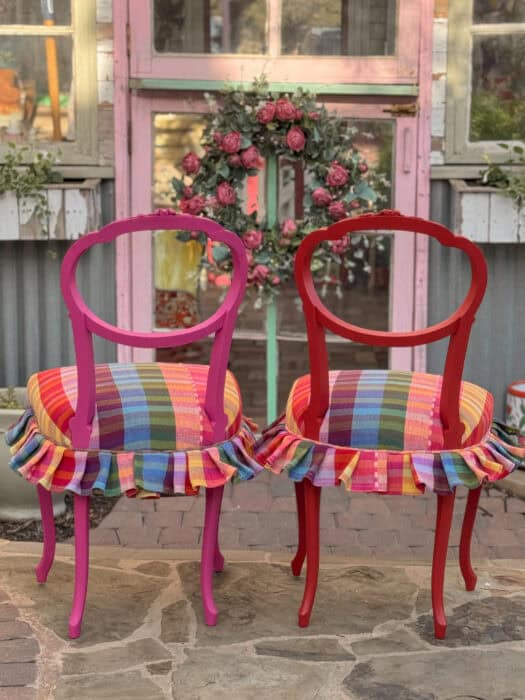 Picture of the back of the two chairs painted pink and red with the bold plaid fabric and a ruffle trim.