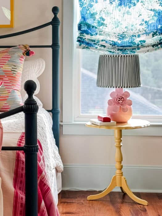 Picture of side table painted yellow with a pink lamp and striped lampshade.