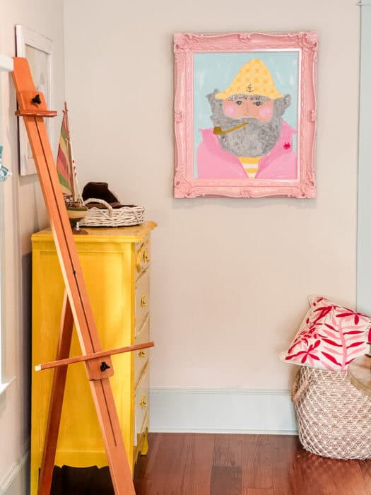 Picture of yellow dresser, art easel, and sailor with a pink frame.