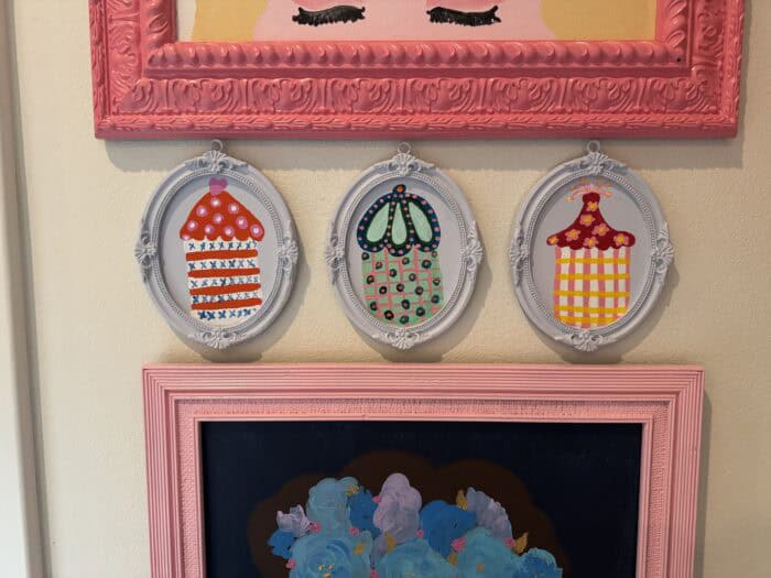Frames and prints in a variety of colors hung on a wall. 