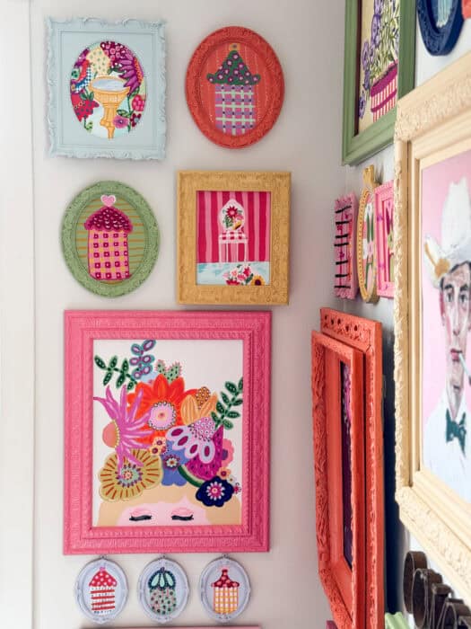 Frames and prints in a variety of colors hung on a wall. 