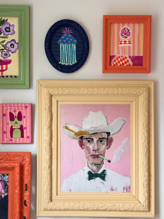 Frames and prints in a variety of colors hung on a wall. 