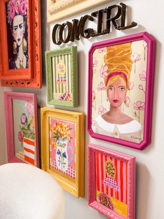Frames and prints in a variety of colors hung on a wall. 
