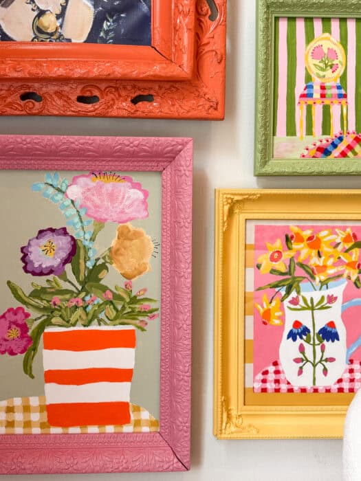 Frames and prints in a variety of colors hung on a wall. 