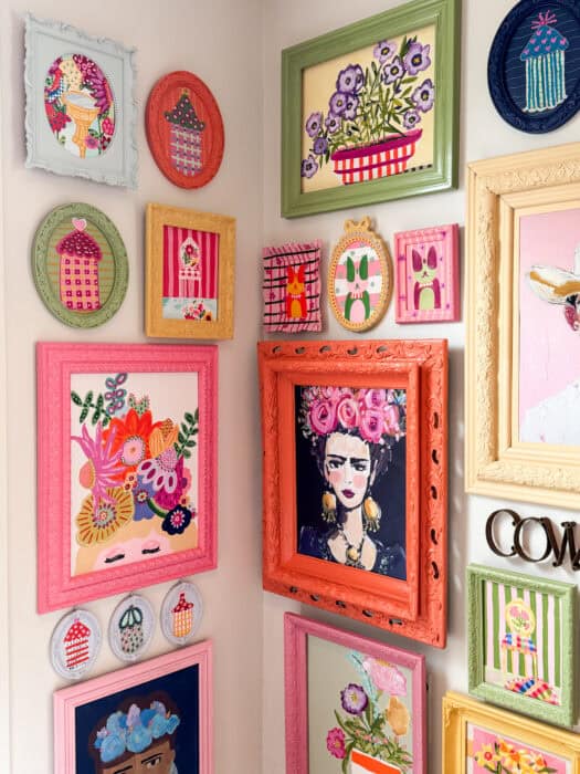 Frames and prints in a variety of colors hung on a wall. 