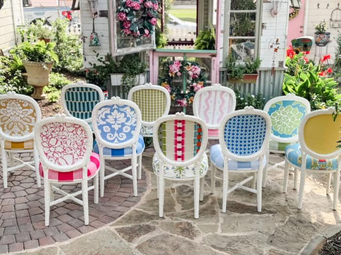 Backside of a whimsical chair set with mixed patterned fabrics in a cottage garden