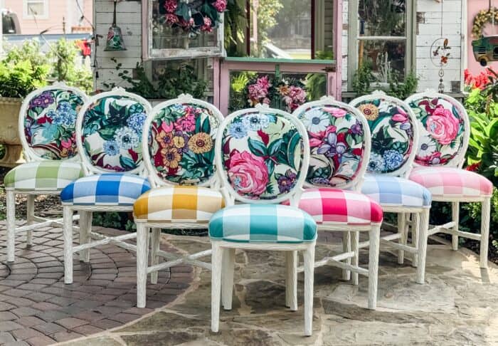 Floral and buffalo check chairs lined up in front of a white garden shed