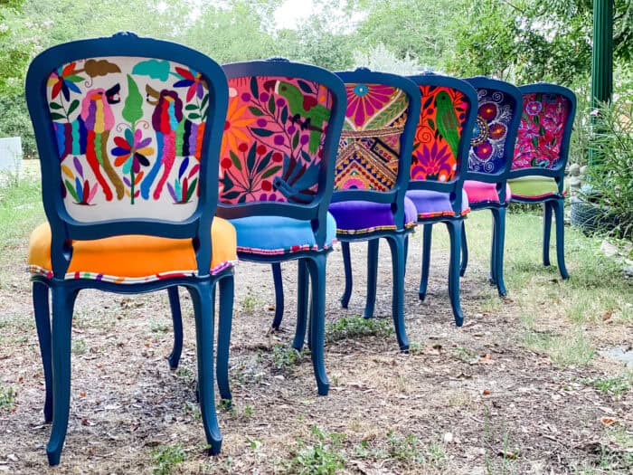 Navy painted chairs with Otomí embroidered backs and colorful velvet seats