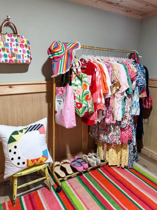 Colorful closet office with pink desk, striped rug, and embroidered curtain