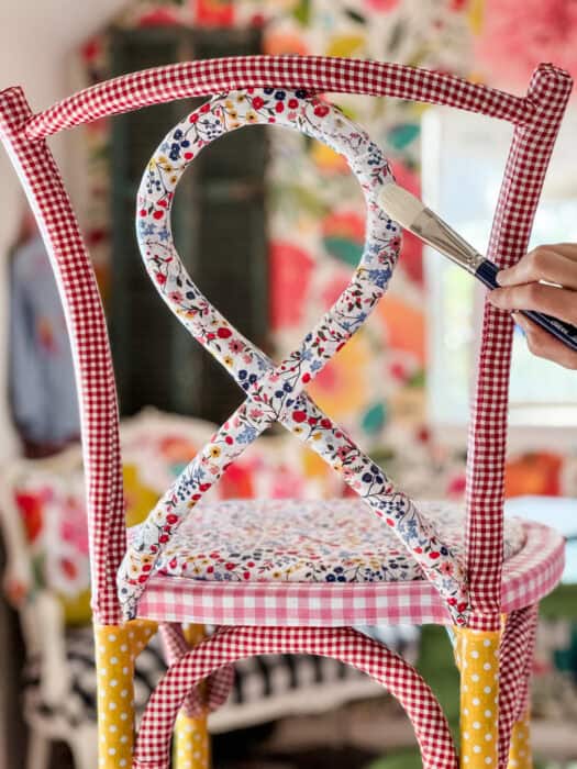 The chair with glue being brushed on with a paintbrush.