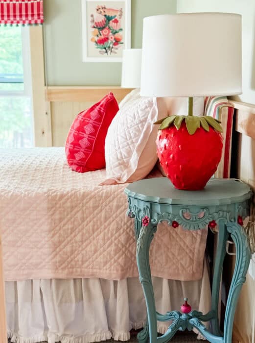 Striped headboard with red pillow and strawberry lamps in colorful cabin bedroom