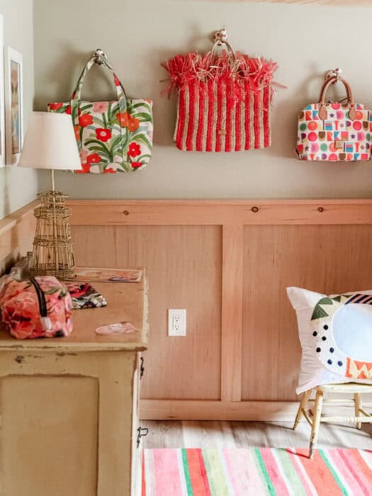 Colorful closet office with pink desk, striped rug, and embroidered curtain